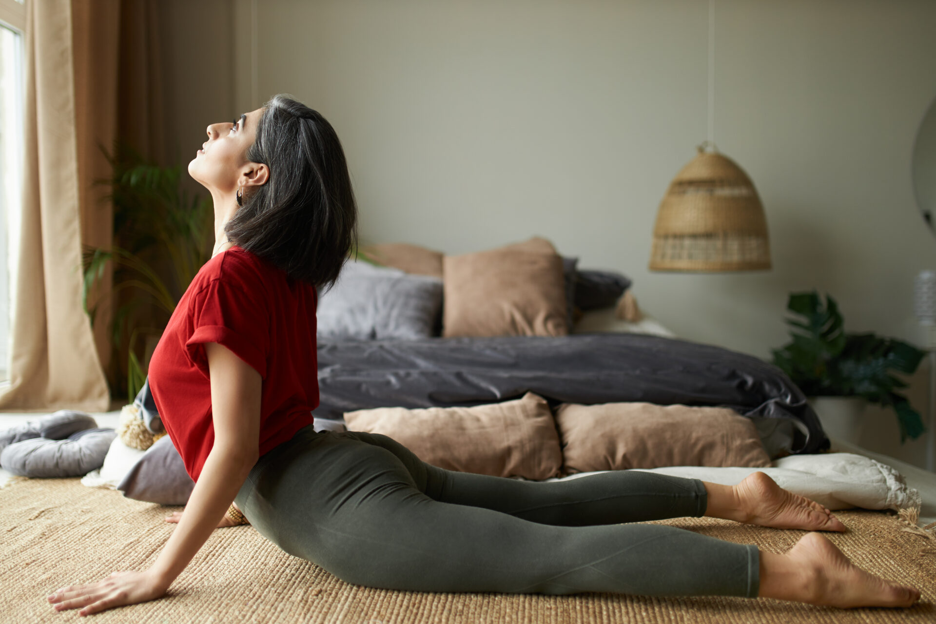 Side view of sporty barefoot girl with strong flexible body exercising at home doing urdhva mukha svanasana or upward-facing dog pose. Young female backbending in yoga sequence or vinyasa flow